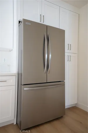 a close view of a refrigerator in kitchen and white cabinets