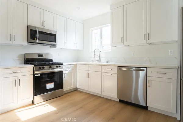 a kitchen with granite countertop white cabinets and stainless steel appliances