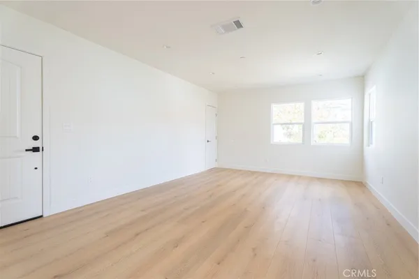 an empty room with wooden floor and window