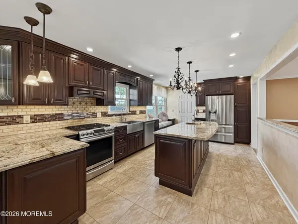 a kitchen with stainless steel appliances granite countertop a stove a sink dishwasher a refrigerator and a oven with wooden floor