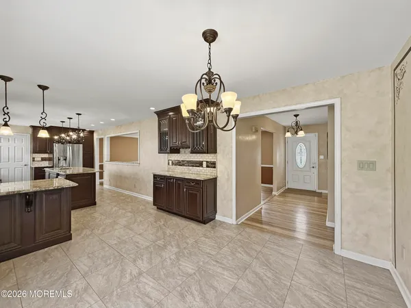a view of a kitchen with granite countertop a sink and dishwasher a stove top oven with wooden floor