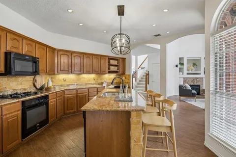 a kitchen with granite countertop wooden cabinets a stove a oven a dining table and chairs