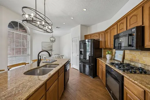 a kitchen with stainless steel appliances granite countertop a sink a stove and a refrigerator