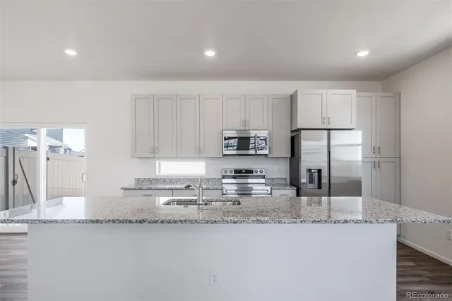 a kitchen with stainless steel appliances granite countertop a sink a stove a refrigerator a microwave and cabinets