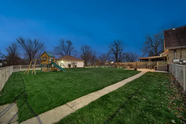a view of a house with a big yard and large trees