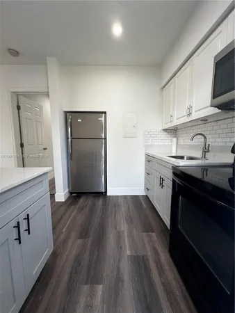 a kitchen with granite countertop a sink cabinets and wooden floor
