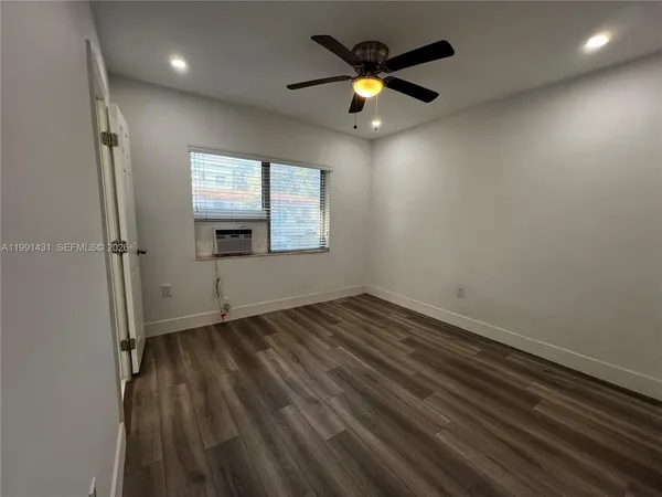 an empty room with a window and a ceiling fan