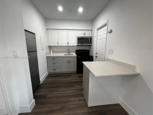 a kitchen with a sink a refrigerator a stove top oven and wooden floor