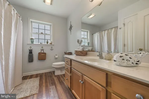 a bathroom with a granite countertop sink a toilet and a window