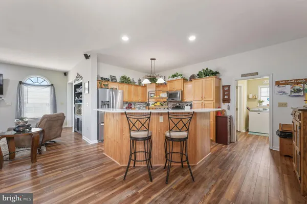 a kitchen with stainless steel appliances kitchen island granite countertop a table chairs and a refrigerator