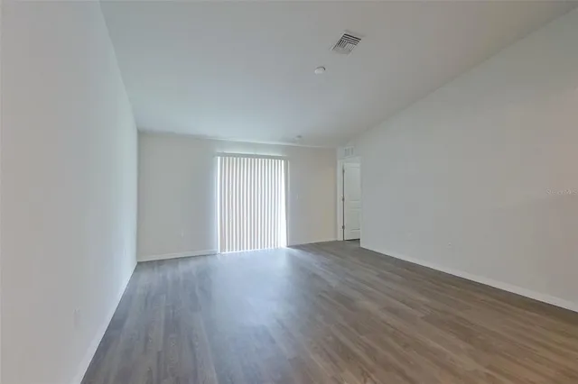 a view of an empty room with wooden floor and window