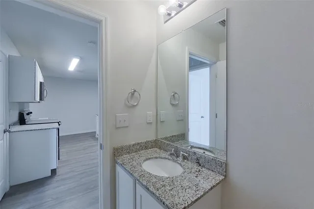 a bathroom with a granite countertop sink a mirror and a shower