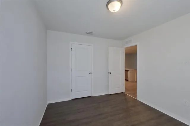 a view of an empty room with wooden floor and closet