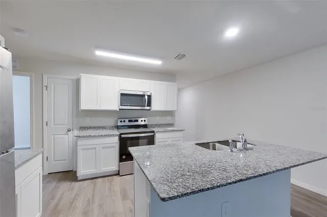 a kitchen with stainless steel appliances granite countertop a sink stove and refrigerator