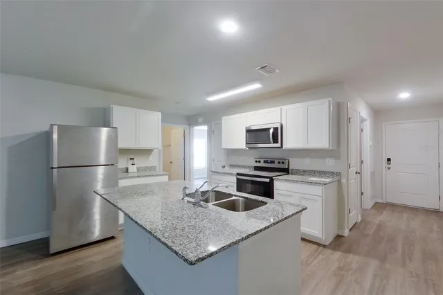 a kitchen with stainless steel appliances granite countertop a sink stove microwave and refrigerator