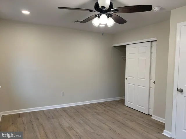 an empty room with wooden floor closet and fan