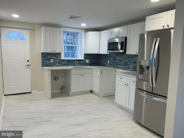 a kitchen with stainless steel appliances granite countertop a refrigerator a stove a sink and a refrigerator