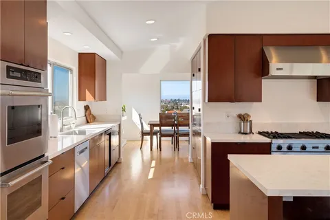 a kitchen with stainless steel appliances a stove a sink a microwave a center island and cabinets
