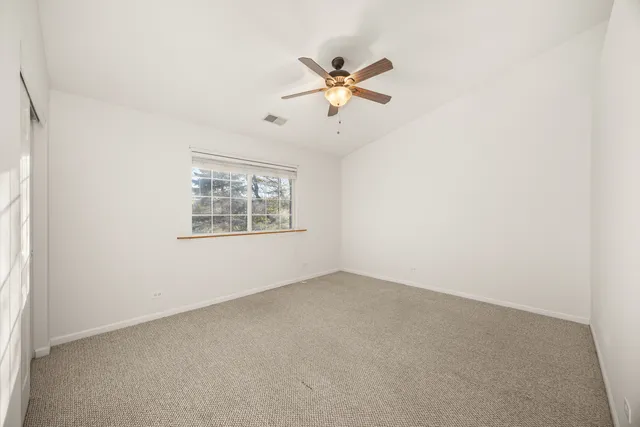 an empty room with a window and a fan