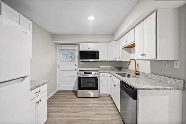 a kitchen with stainless steel appliances granite countertop a stove a sink and a microwave