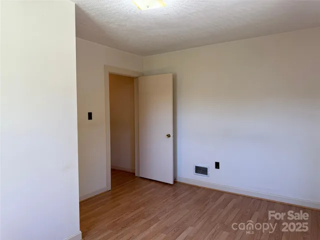 a view of an empty room with wooden floor and a ceiling fan