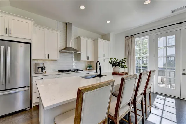 a kitchen with stainless steel appliances a stove a refrigerator a dining table and chairs