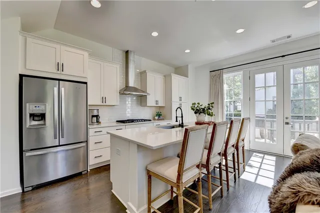 a kitchen with stainless steel appliances a refrigerator a stove a dining table and chairs