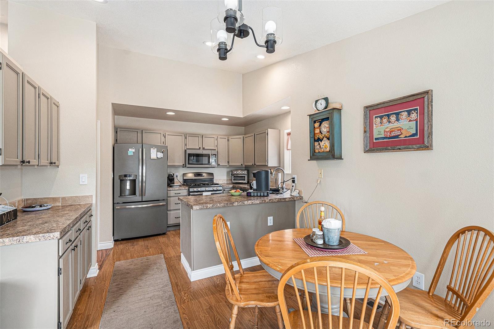 15482 Gadsden Drive Brighton, CO 80603 - Photo 13 of 43 a kitchen with stainless steel appliances kitchen island granite countertop a table chairs and a refrigerator