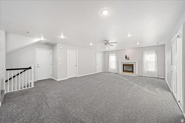 7 Reflection Way St. George, UT 84770 - Photo 21 of 54 Unfurnished living room with carpet, a fireplace, and a ceiling fan