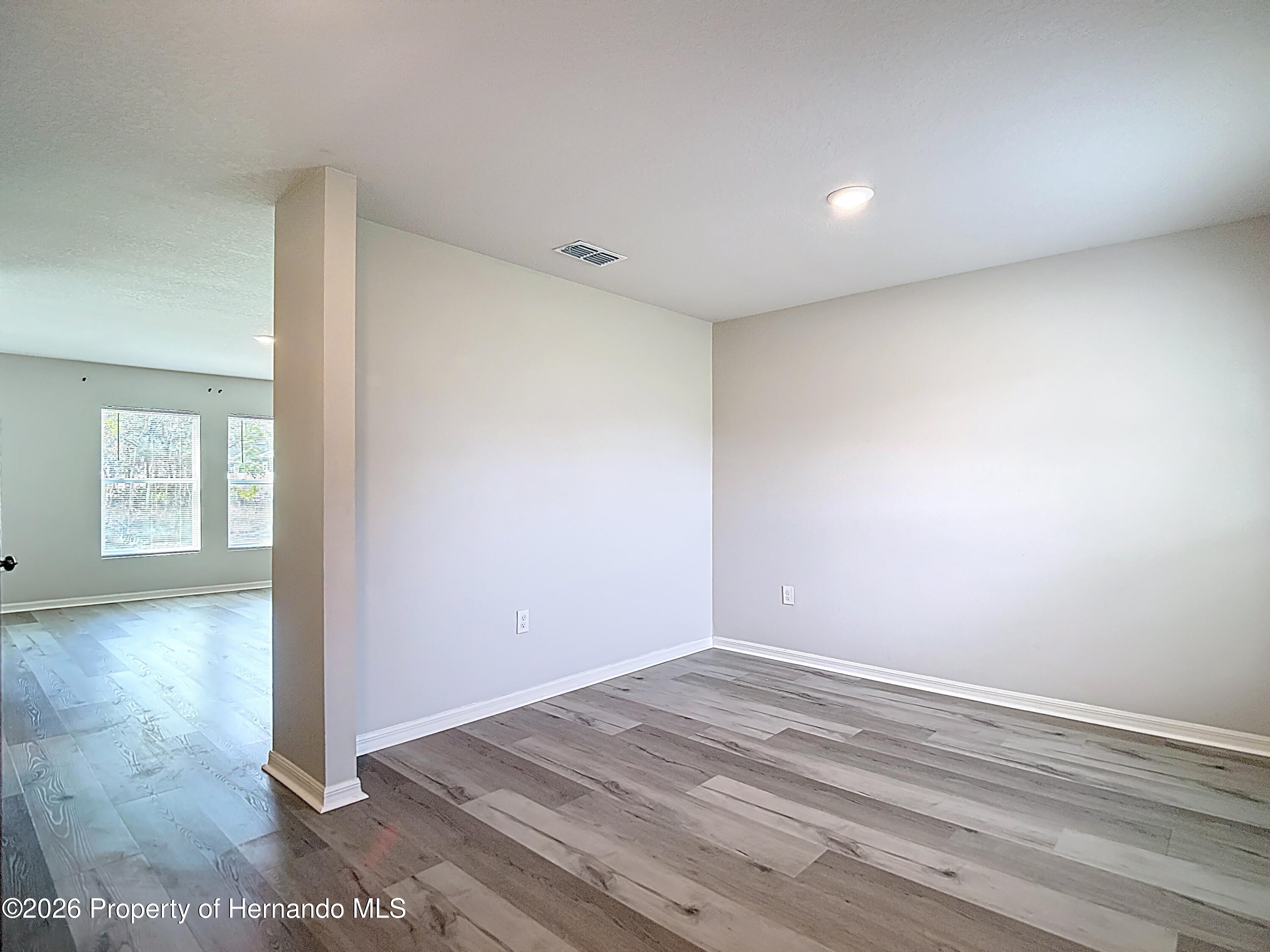 11374 Marcella Avenue Weeki Wachee, FL 34614 - Photo 10 of 70 an empty room with wooden floor and windows