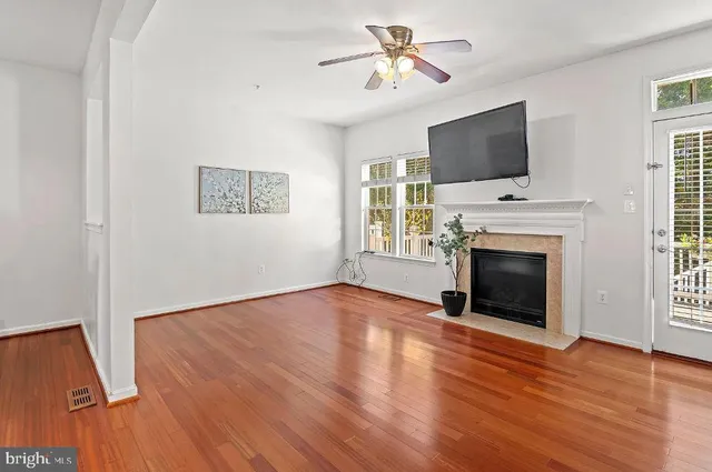 a view of a livingroom with a fireplace a ceiling fan and windows