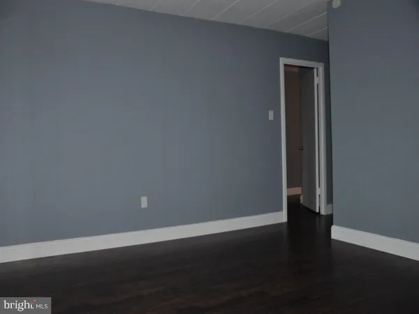 a view of an empty room with wooden floor and closet