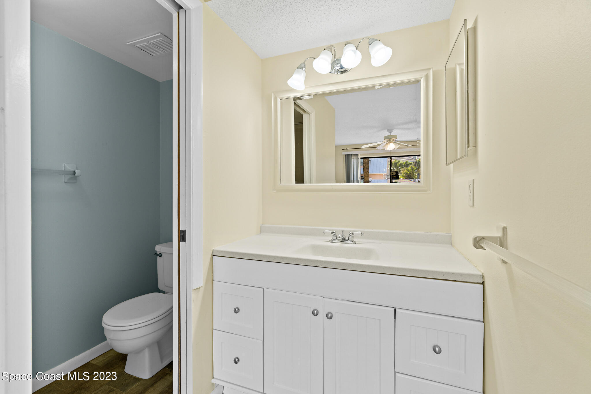 6655 Ridgewood Avenue, Unit 104 Cocoa Beach, FL 32931 - Photo 18 of 25 a bathroom with a toilet sink vanity and mirror