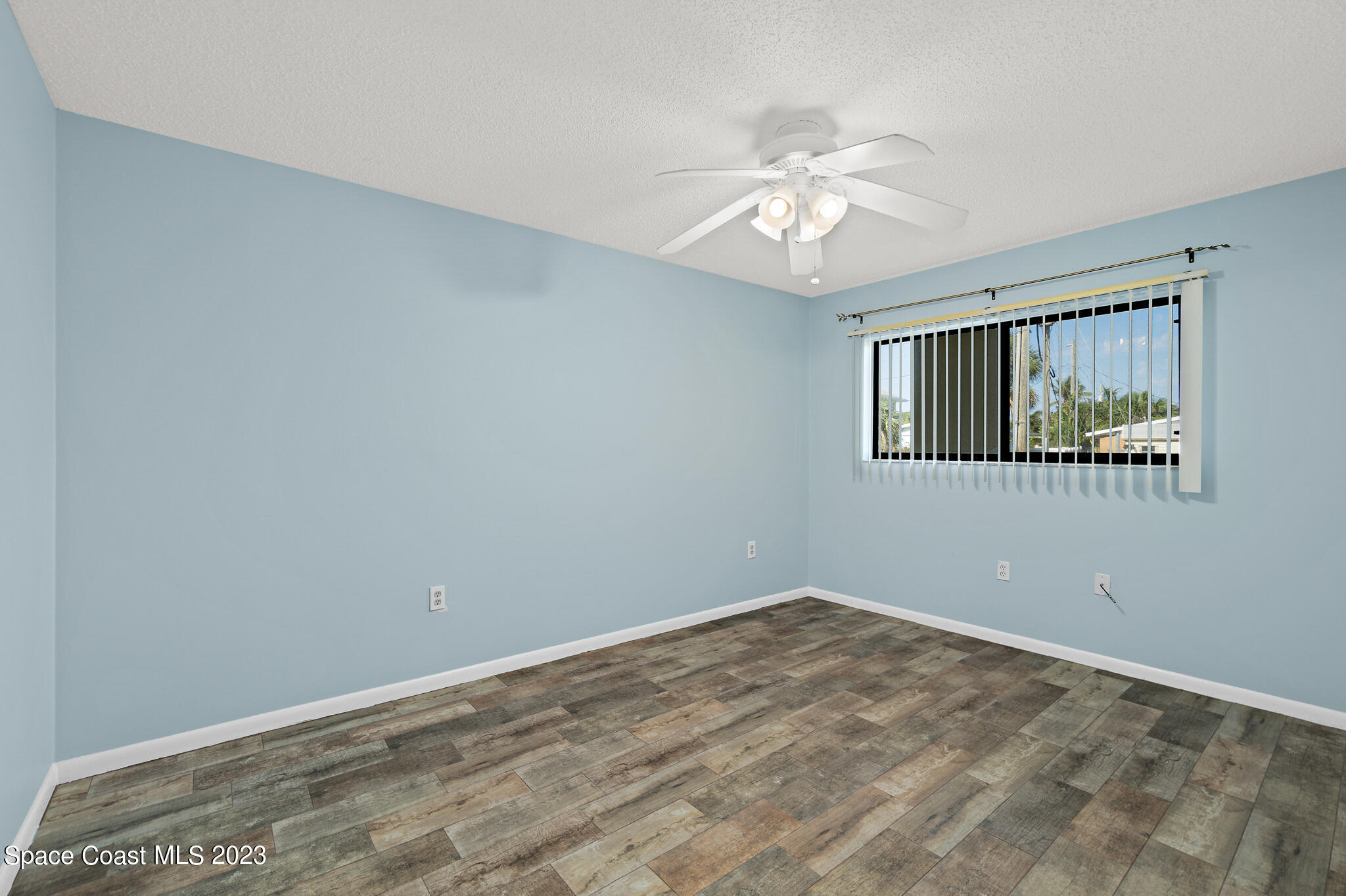 6655 Ridgewood Avenue, Unit 104 Cocoa Beach, FL 32931 - Photo 20 of 25 an empty room with wooden floor fan and windows