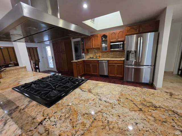 a kitchen with stainless steel appliances granite countertop a refrigerator and a stove top oven