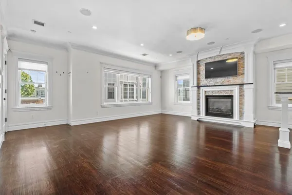 an empty room with windows fireplace and wooden floor