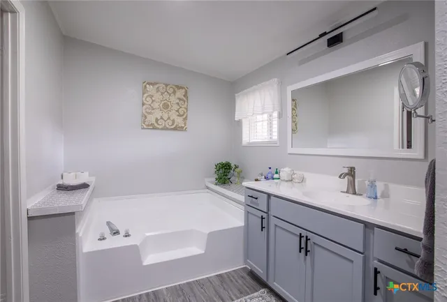 a bathroom with a tub sink and mirror