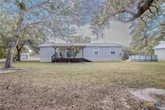 a view of a house with a yard and large tree