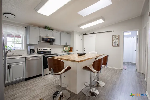 a kitchen with kitchen island granite countertop a sink a counter space stainless steel appliances and cabinets