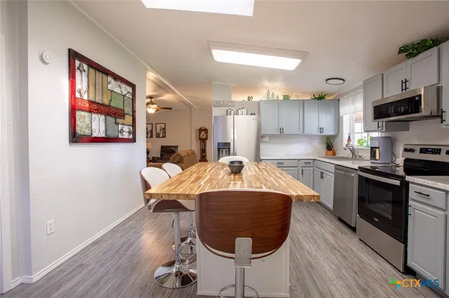 a kitchen with kitchen island stainless steel appliances a stove a sink a microwave and wooden floors