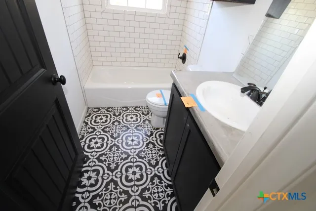 a bathroom with a sink and mirror with bathtub