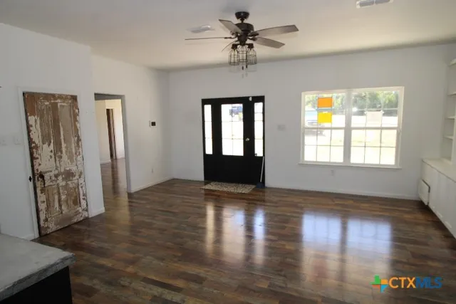 a view of an empty room with window and wooden floor