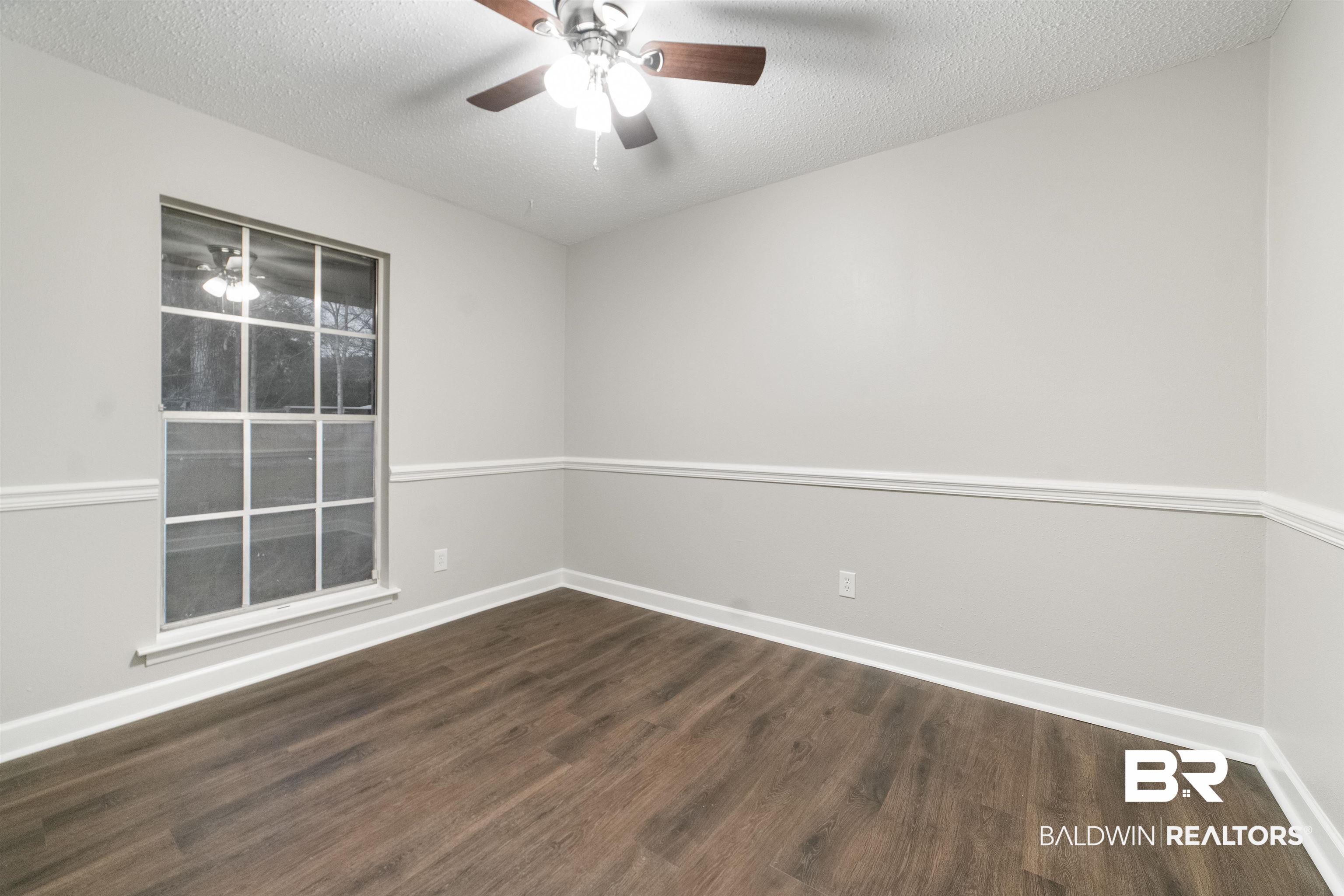 11833 Old Moffat Road Wilmer, AL 36587 - Photo 15 of 23 Spare room with a textured ceiling, dark wood-type flooring, a ceiling fan, and baseboards