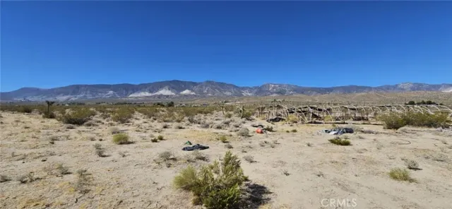 a view of a dry field with mountains in the background