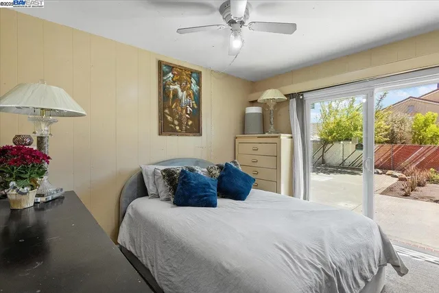 a bedroom with a bed potted plant on the dresser and a large window