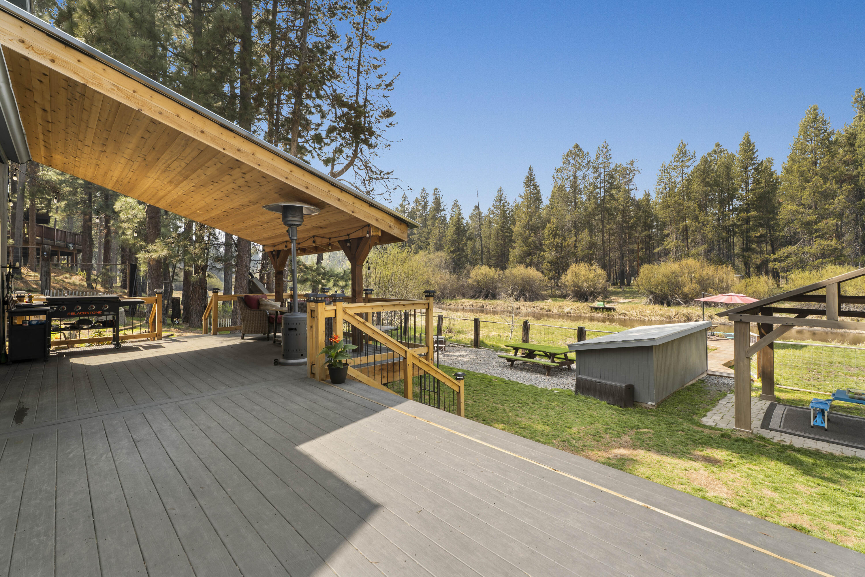 17062 Milky Way Bend, OR 97707 - Photo 21 of 39 Grilling deck steps down to the lawn, pavilion, and water beyond