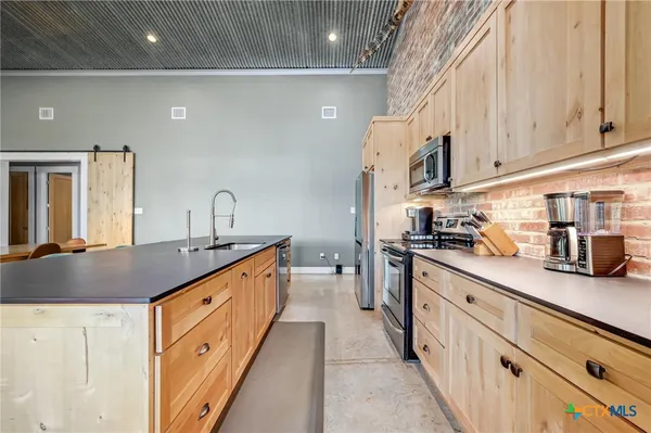 a kitchen with stainless steel appliances granite countertop a stove a sink and white cabinets