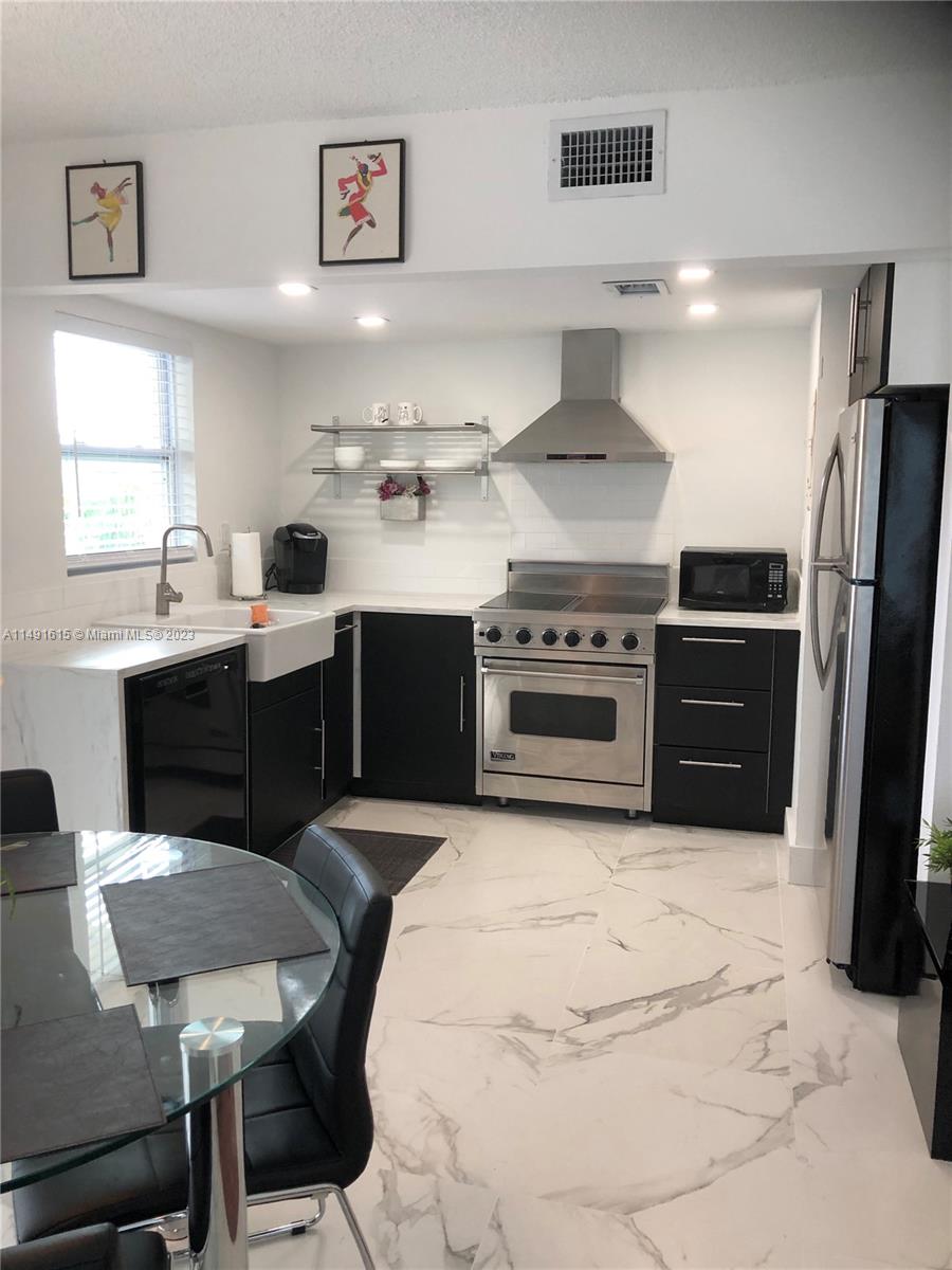 427 Southwest 7th Street, Unit 15 Miami, FL 33130 - Photo 14 of 25 a kitchen with stainless steel appliances a stove a sink island and a refrigerator