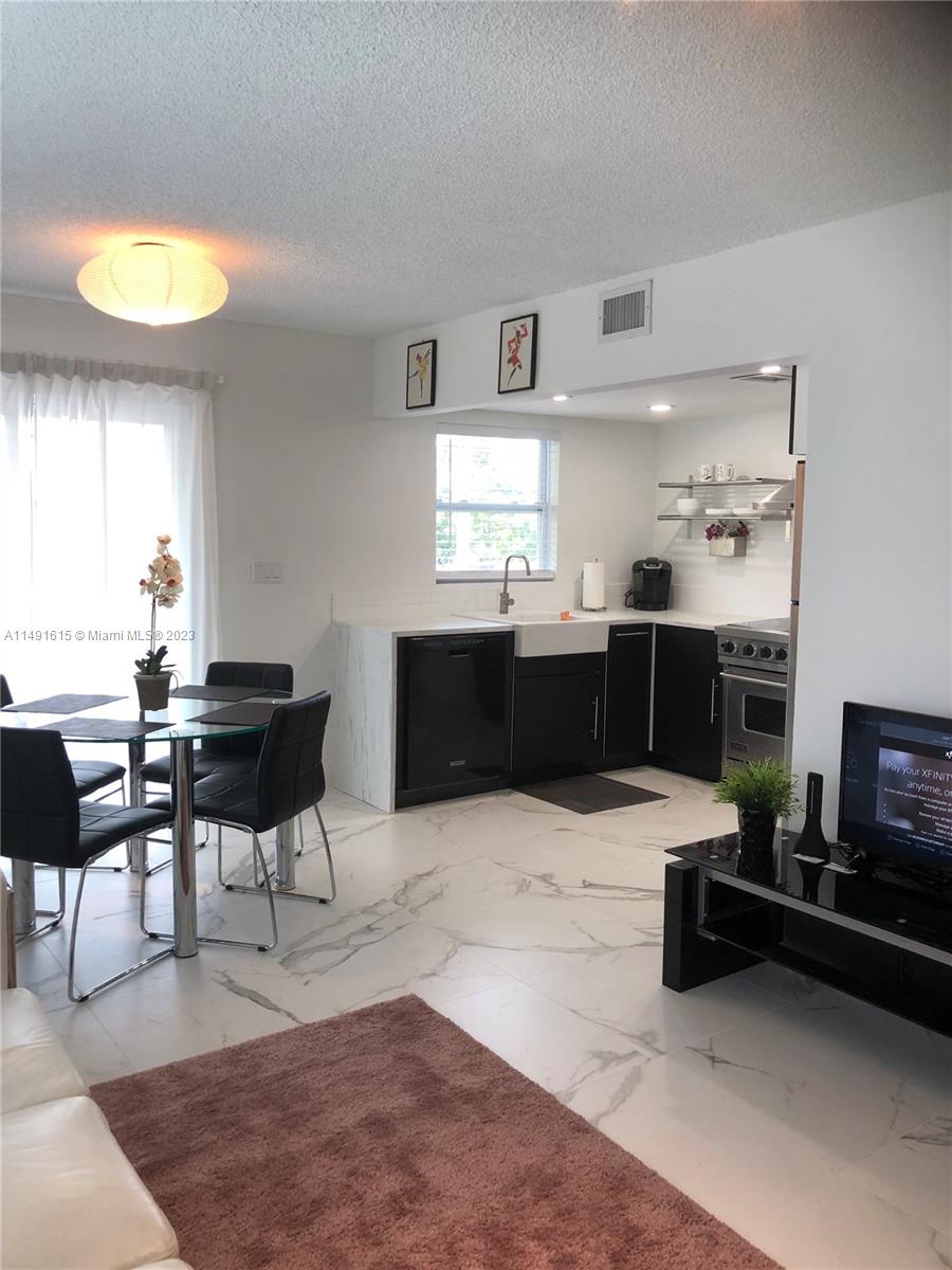 427 Southwest 7th Street, Unit 15 Miami, FL 33130 - Photo 8 of 25 a kitchen with stainless steel appliances kitchen island granite countertop a sink and a stove