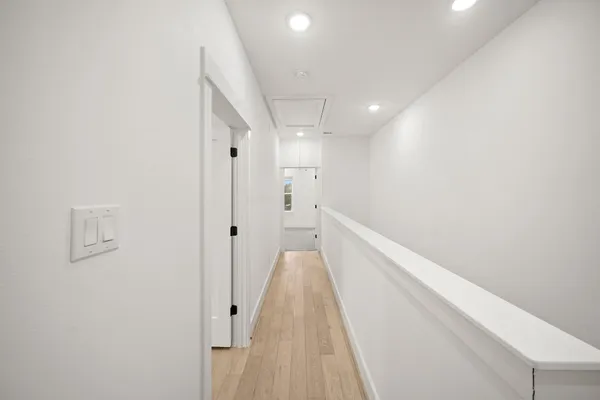 a view of a hallway with wooden floor and a bathroom